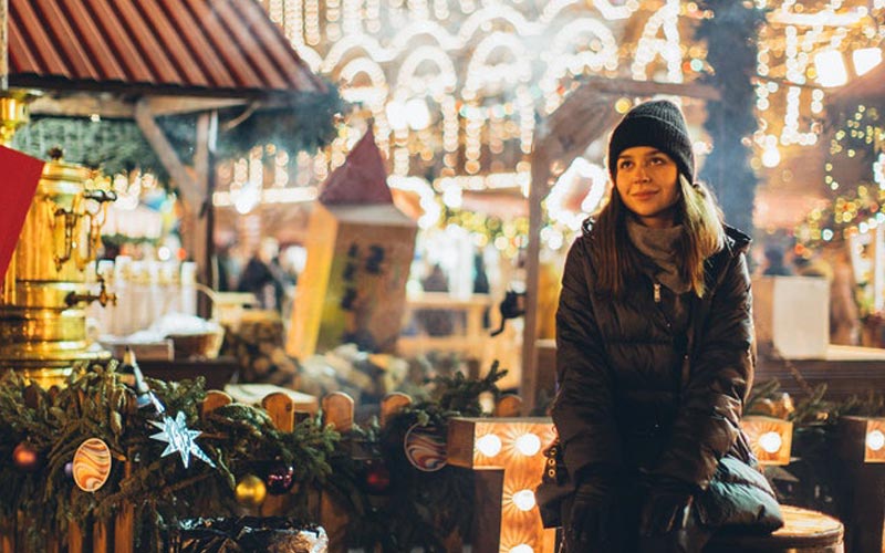 rapariga sentada numa rua de comércio local enfeitada para o Natal