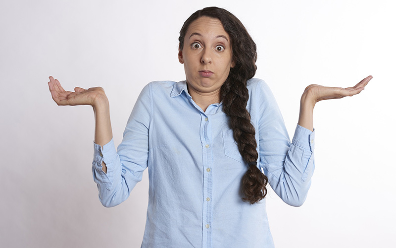 Mulher com os ombros encolhidos e as mãos para cima sem saber o que escolher entre o Tiktok e o Instagram
