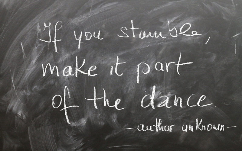 Quadro preto com frase "if you stumble make it part of the dance - author unknown" escrita a giz simbolizando os imprevisto do marketing digital em tempos de quarentena